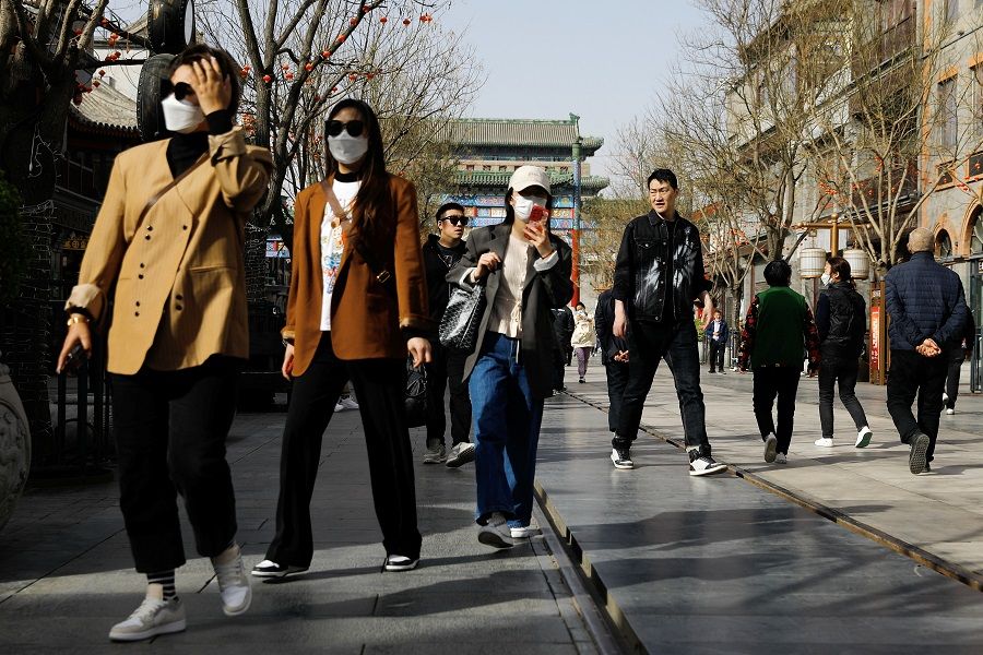 People walk at Qianmen Street, in Beijing, China, 14 March 2023. (Tingshu Wang/Reuters)
