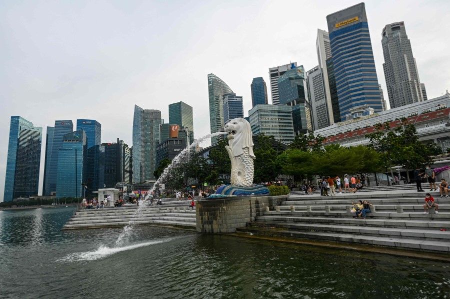 People sit along the steps next to the Merlion statue along the Marina Bay waterfront in Singapore on 1 June 2022. (Roslan Rahman/AFP)
