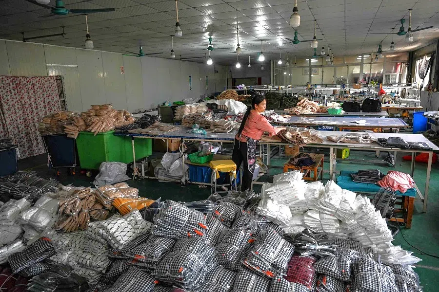 An employee packages garments for a Chinese e-commerce company at a clothing factory in Guangzhou, Guangdong province, China, on 16 April 2025. (Jade Gao/AFP)