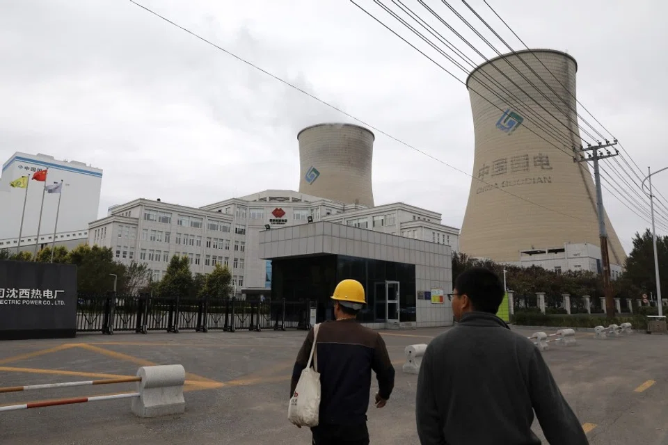 People walk past a China Energy coal-fired power plant in Shenyang, Liaoning province, China, 29 September 2021. (Tingshu Wang/Reuters)
