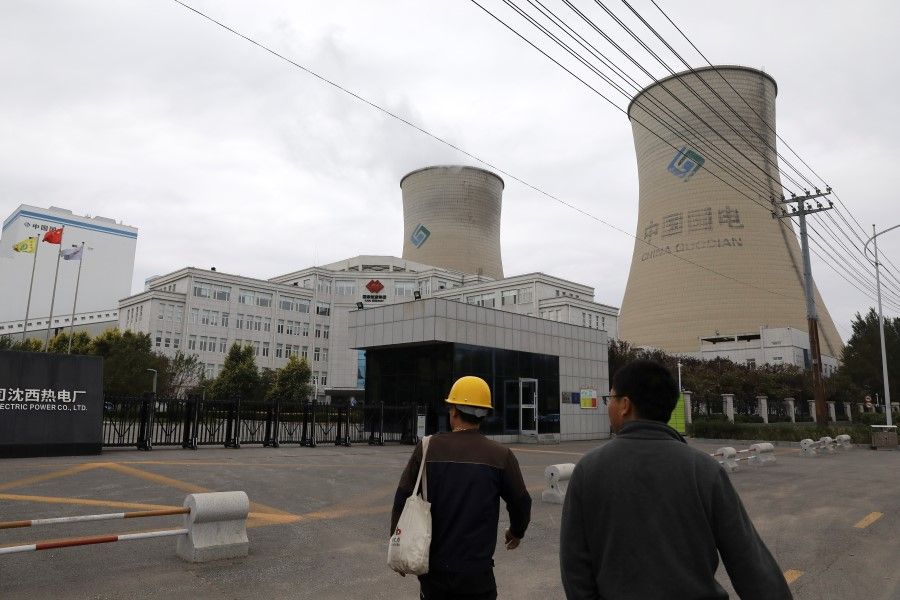People walk past a China Energy coal-fired power plant in Shenyang, Liaoning province, China, 29 September 2021. (Tingshu Wang/Reuters)