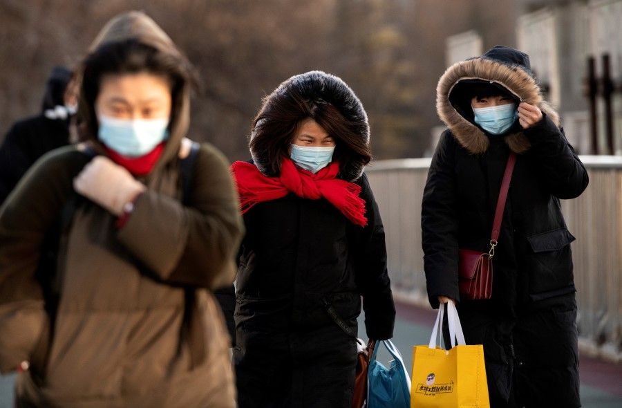 People wrapped up due to freezing weather walk on an overpass in Beijing on 6 January 2021. (Noel Celis/AFP)