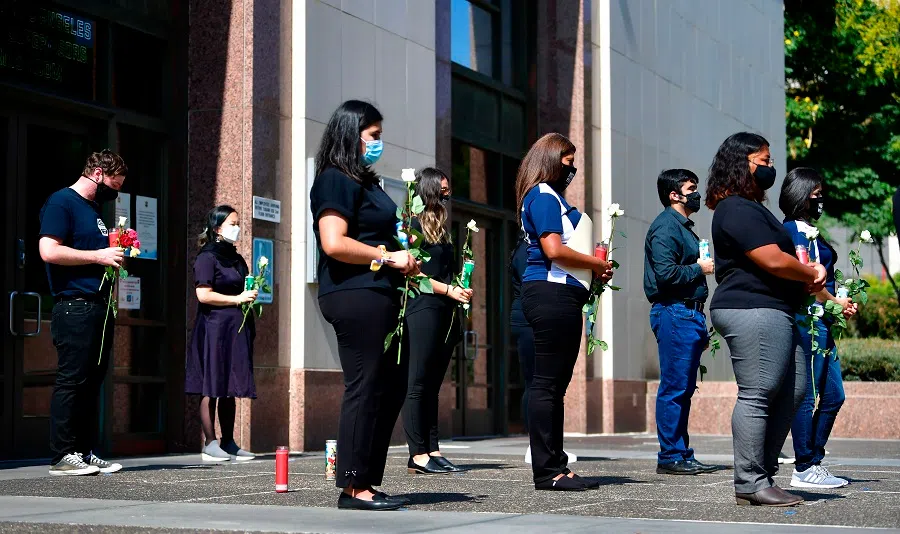 People hold roses while attending a memorial honouring more than 5,700 residents of Los Angeles who lost their lives to the Covid-19 coronavirus on 31 August 2020 in Los Angeles, California. (Frederic J. Brown/AFP)