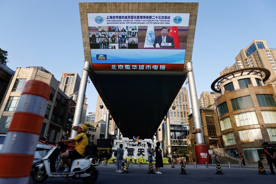 A giant screen broadcasts news footage of Chinese President Xi Jinping attending via video link the meeting of the Shanghai Cooperation Organisation Council of Heads of State, in Beijing, China, 4 July 2023. (Tingshu Wang/Reuters)