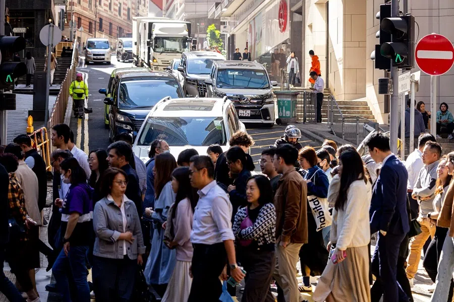 Pedestrians cross a road in the Central district in Hong Kong, China, on 20 November 2023. (Paul Yeung/Bloomberg)