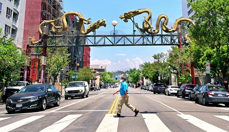 A pedestrian wears a facemask while crossing the street near the Chinatown Gateway Monument in Los Angeles, California, US on 14 July 2022. (Frederic J. Brown/AFP)