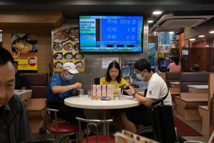 A television shows a live broadcast of the vote count on a draft decision for new national security legislation for Hong Kong, taking place at the National People's Congress in Beijing, at a diner in Hong Kong, 28 May 2020. (Roy Liu/Bloomberg)