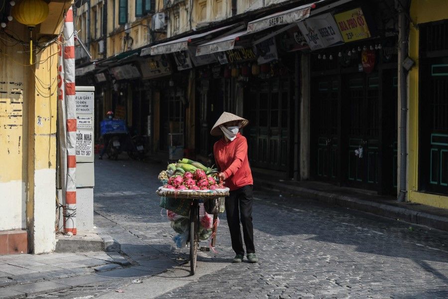 A fruit vendor pushes her bicycle on a street in Hanoi on 3 March 2022. (Nhac Nguyen/AFP)