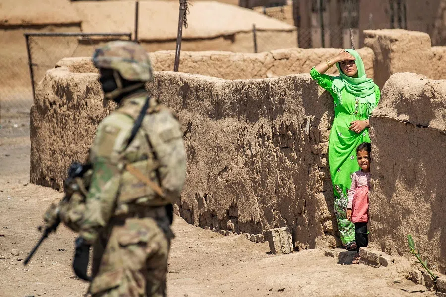 A US soldier stands by as a local woman and child look on during a US military patrol in Rumaylan (Rmeilan) in Syria's Al-Hasakeh province on 22 June 2021. (Delil Souleiman/AFP)