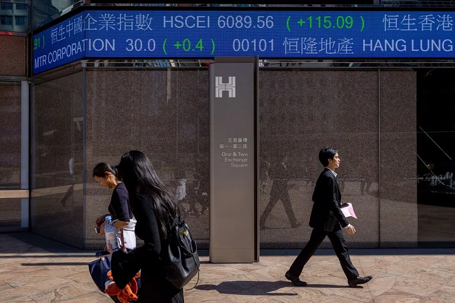 Pedestrians walk past the electronic ticker displaying stock figures at the Exchange Square Complex, which houses the Hong Kong Stock Exchange, in Hong Kong, China, on 20 November 2023. (Paul Yeung/Bloomberg)