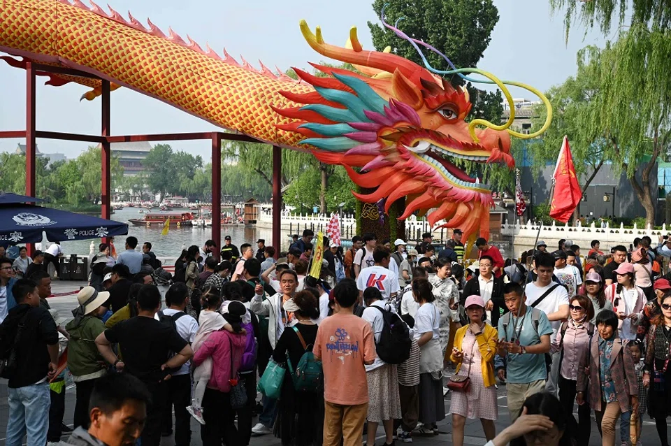 People walk past a giant dragon at a tourist area in Beijing, China, on 4 May 2024. (Greg Baker/AFP)