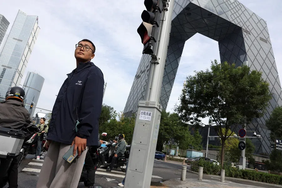 A man waits at an intersection in the central business district of Beijing, China, on 11 October 2025.