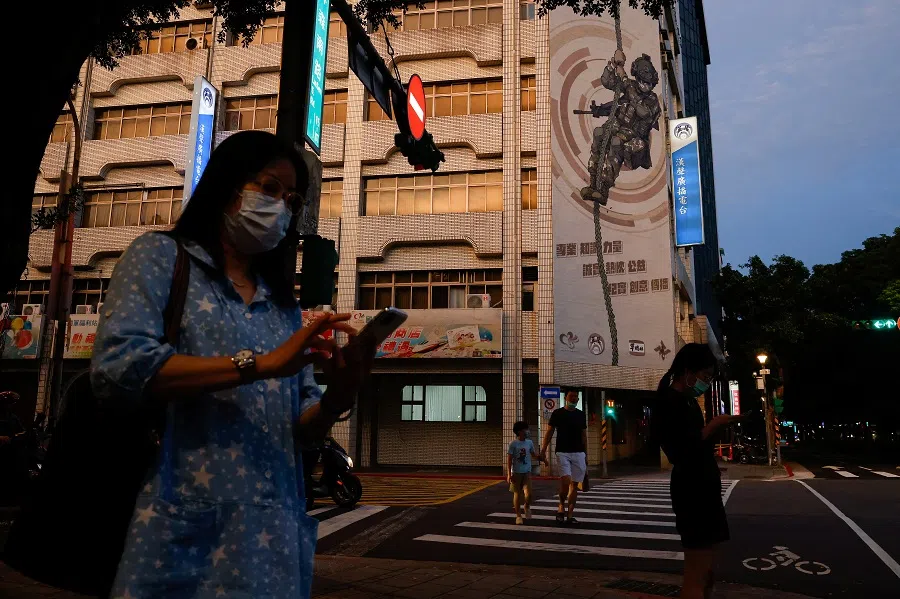 People wait to cross the street in front of a building with a military recruitment advertisement in Taipei, Taiwan, on 18 August 2023. (Ann Wang/Reuters)