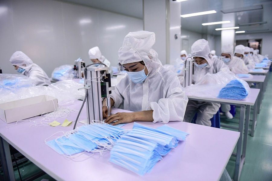 This file photo taken on 16 April 2020 shows workers producing face masks at a factory in Shenyang, Liaoning, China. (STR/AFP)