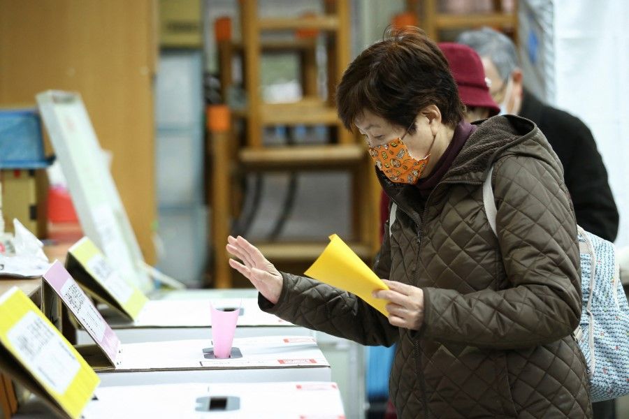 A woman casts her vote at a polling station while participating in a four-question referendum in Taipei, Taiwan, 18 December 2021. (Annabelle Chih/Reuters)