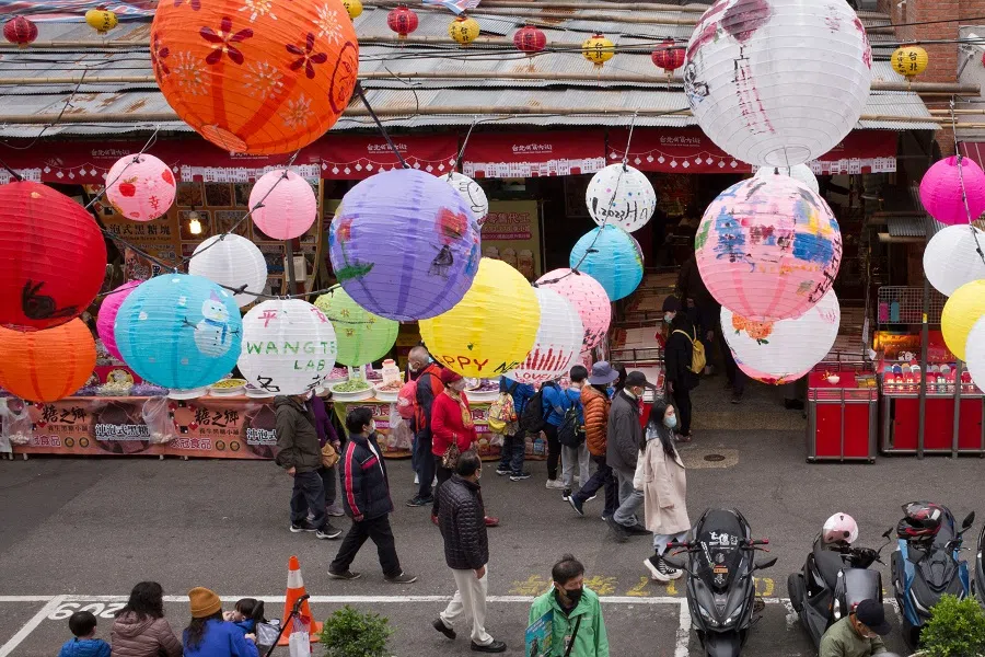 People walk under lanterns at the traditional market along Dihua Street in Taipei on 17 January 2023, ahead of the Lunar New Year of the Rabbit on 22 January. (Photo by Sam Yeh / AFP)