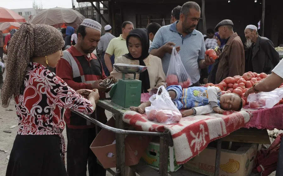 An ethnic Uighur boy sleeps on a stand as customers select tomatoes at a market in Aksu, Xinjiang Uighur Autonomous Region, 13 May 2012. (Stringer/Reuters)