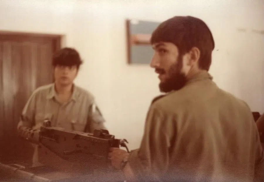 An officer at a military base demonstrating how to dismantle a machine gun.