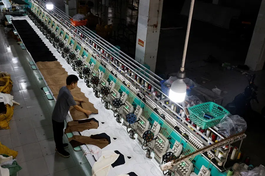 A worker sets up fabric on an automated embroidery machine at a garment factory in Panyu District, Guangzhou, Guangdong province, China, on 27 July 2026.