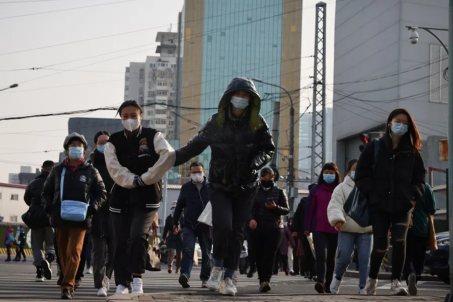 People cross a street on the day Chinese President Xi Jinping and his US counterpart Joe Biden hold a virtual summit, in Beijing, China, 16 November 2021. (Thomas Peter/Reuters)