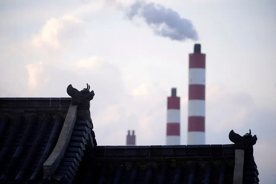 Chimneys of a coal-fired power plant are seen behind a gate in Shanghai, China, on 21 October 2021. (Aly Song/Reuters)
