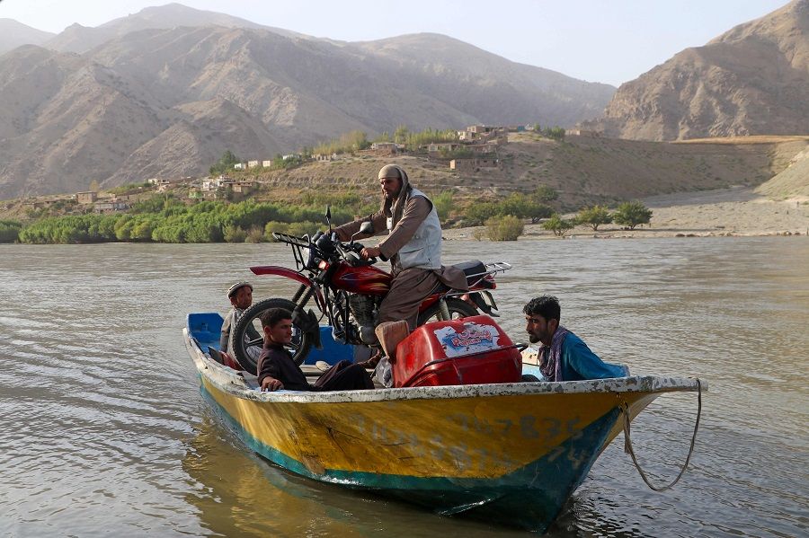 Afghan men ferry a motorcycle on a boat across the Kokcha river on the outskirts of Fayzabad district of Badakhshan province, Afghanistan on 20 August 2023. (Omer Abrar/AFP)