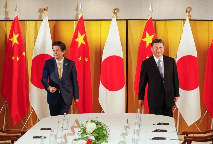 Shinzo Abe, Japan's prime minister, left, and Xi Jinping, China's president, prepare to take their seats during a bilateral meeting ahead of the Group of 20 (G-20) summit in Osaka, Japan, on 27 June 2019. (Kimimasa Mayama/Bloomberg)