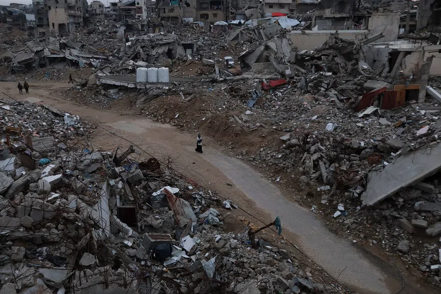 Palestinians walk among the rubble of buildings destroyed during the Israeli offensive, amid a ceasefire between Israel and Hamas, in Khan Younis, in the southern Gaza Strip, on 24 February 2025. (Ramadan Abed/Reuters)