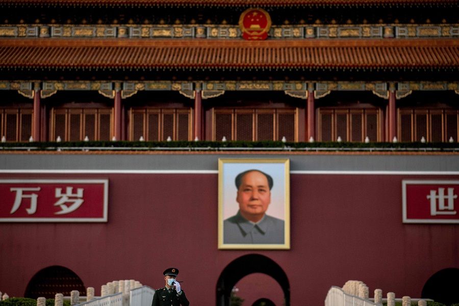 A paramilitary police officer wearing a face mask talks on his radio transmitter as he stands in front of the portrait of late communist leader Mao Zedong at Tiananmen Gate in Beijing on 13 October 2020. (Nicolas Asfouri/AFP)