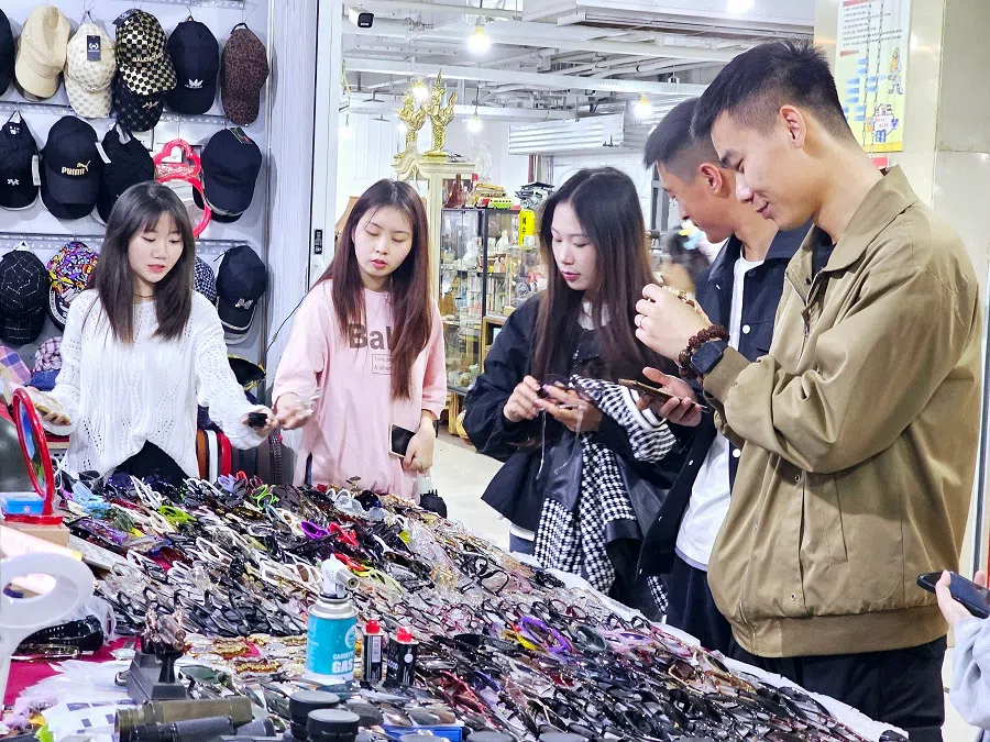 Young people browsing second-hand items at the Dongjiaxi flea market in Chongqing.