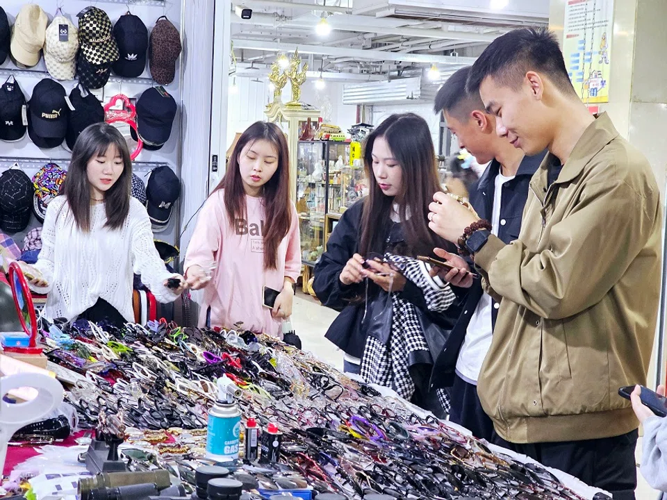 Young people browsing second-hand items at the Dongjiaxi flea market in Chongqing.