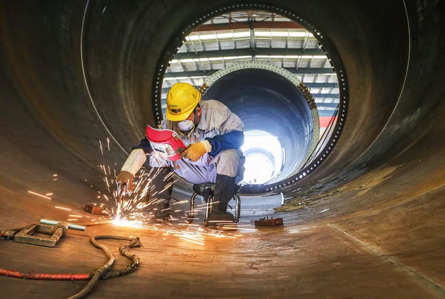 An employee works on a wind turbine tower at a factory in Lianyungang, Jiangsu province, China, on 7 October 2023. (AFP)