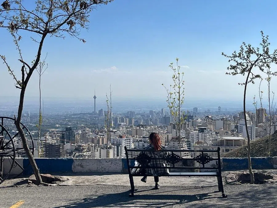 A woman sits on a bench overlooking the city at Pardisan Park in Tehran on 22 April 2026. (AFP)