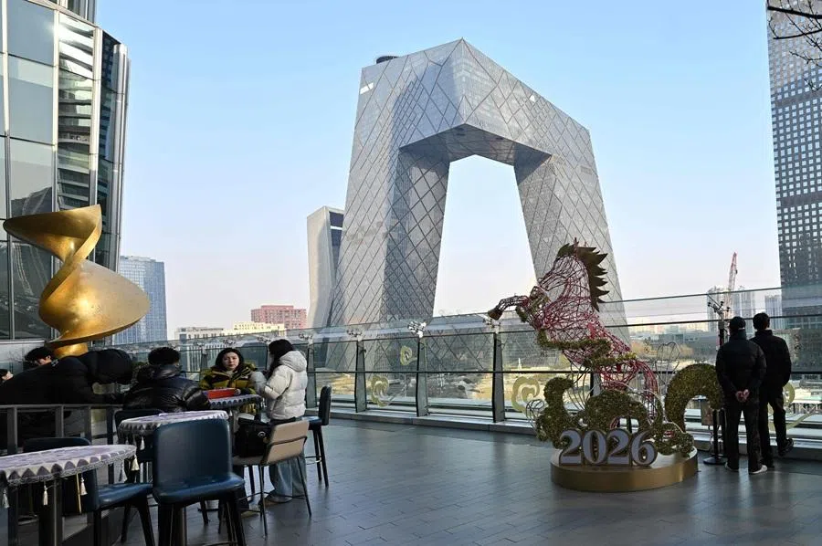 People relax at a shopping mall looking at highrise buildings in Beijing on 14 January 2026. (Adek Berry/AFP)
