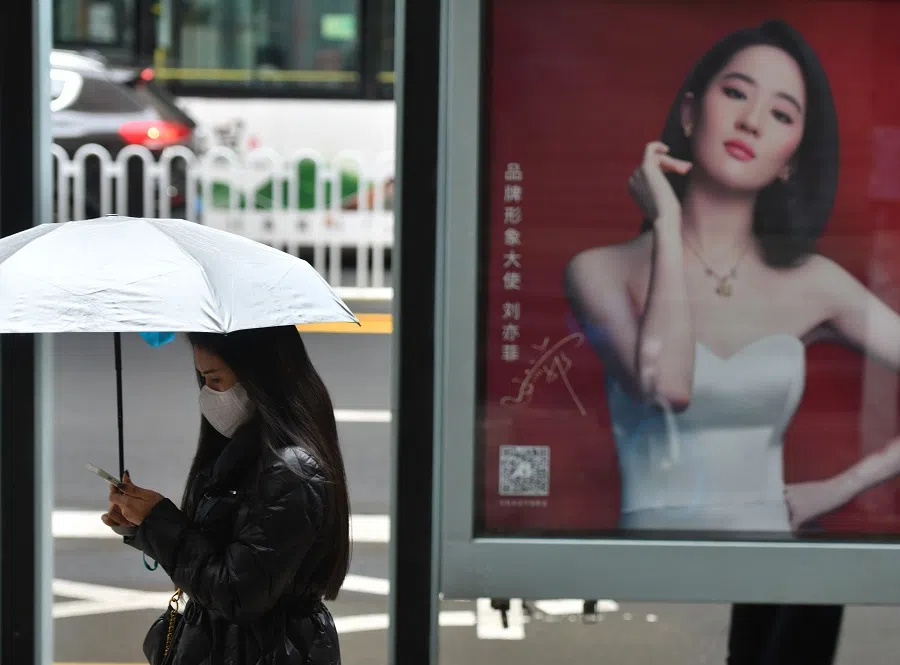 A woman wearing a down jacket walks past a bus stop in Kunming, Yunnan province, China, 22 November 2021. (CNS)