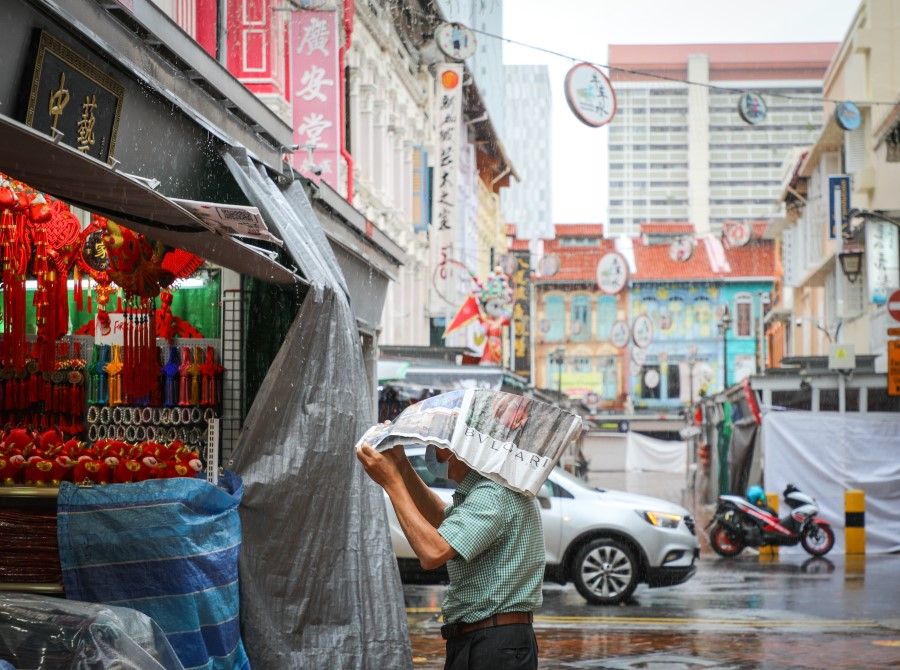A man uses a newspaper against the rain in Chinatown, Singapore, 1 January 2021. (SPH Media)