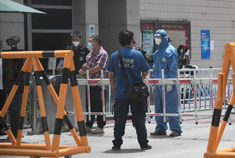 A security personnel wearing a protective suit stands guard at a residential area under lockdown near Yuquan East Market in Beijing, 15 June 2020. (Noel Celis/AFP)