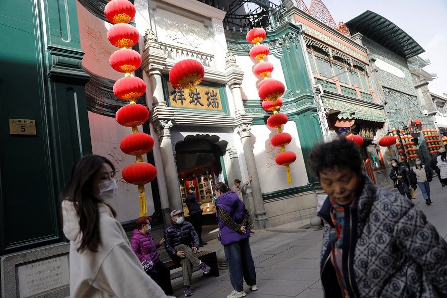 People walk past shops near Qianmen Street, in Beijing, China, 14 March 2023. (Tingshu Wang/Reuters)