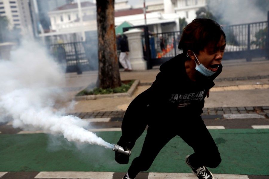 A demonstrator holds a tear gas canister to be thrown back to police during a clash between demonstrators and police following a protest against the new so-called omnibus law, in Jakarta, Indonesia, 13 October 2020. (Willy Kurniawan/REUTERS)