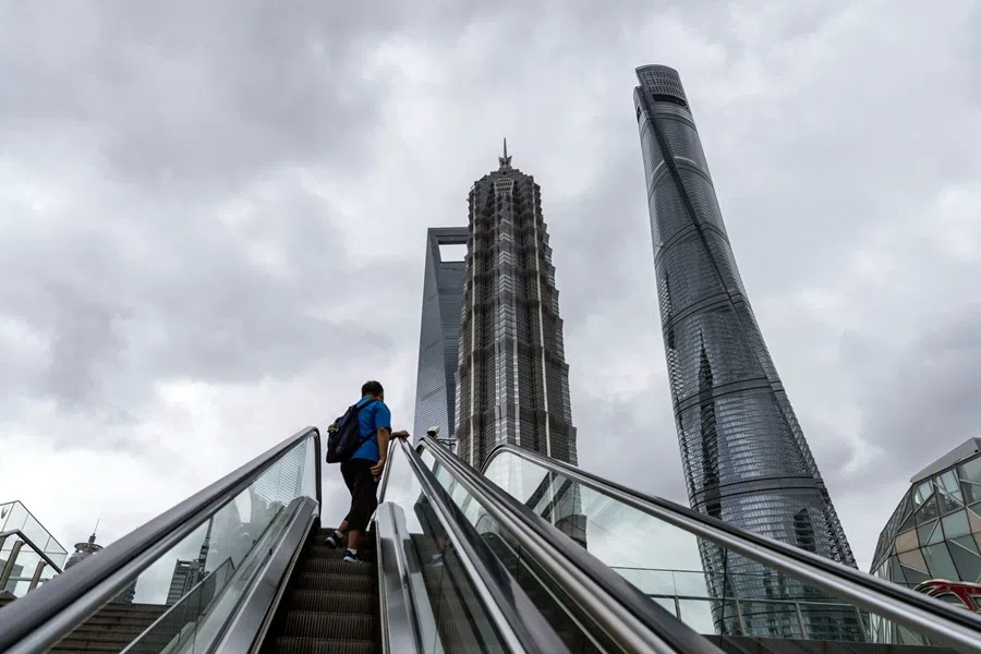 A pedestrian on an escalator in front of buildings in Pudong’s Lujiazui financial district in Shanghai, China, on 10 September 2025.