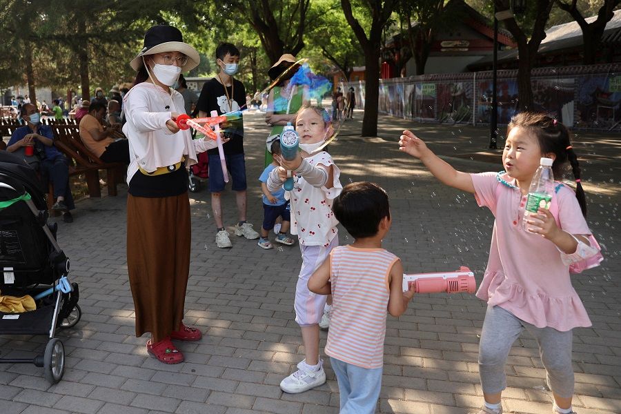 Children play with bubbles at a park in Beijing, China, 4 June 2022. (Tingshu Wang/Reuters)