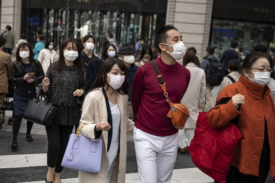 People cross a street in Tokyo's Ginza area in Japan, on 19 March 2022. (Charly Triballeau/AFP)
