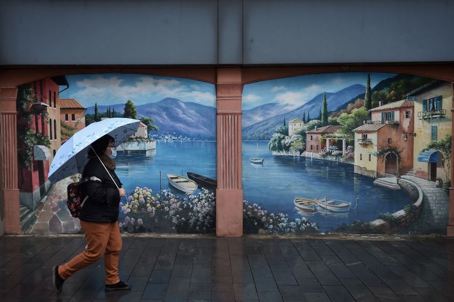 This photo taken on 28 February 2020 shows a resident walking past a mural in Wuhan, in China's central Hubei province. (STR/AFP)
