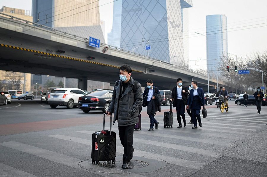 Pedestrians cross a street with their luggage in the central business district of Beijing, China on 8 March 2021. (Wang Zhao/AFP)