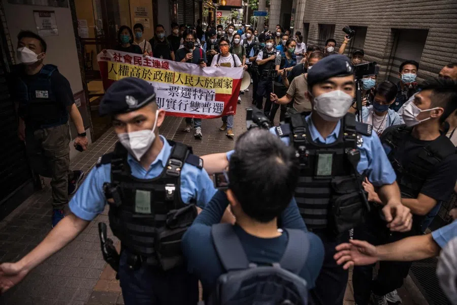 Police (front) usher the media as three members of the League of Social Democrats march on a street during a protest against the selection process of the city's chief executive in Hong Kong on 8 May 2022. (Dale de la Rey/AFP)