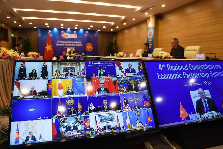Vietnam's Prime Minister Nguyen Xuan Phuc is pictured on the screen (right) as he addresses his counterparts during the 4th Regional Comprehensive Economic Partnership (RCEP) Summit at the Association of Southeast Asian Nations (ASEAN) summit being held online in Hanoi on 15 November 2020. (Nhac Nguyen/AFP)