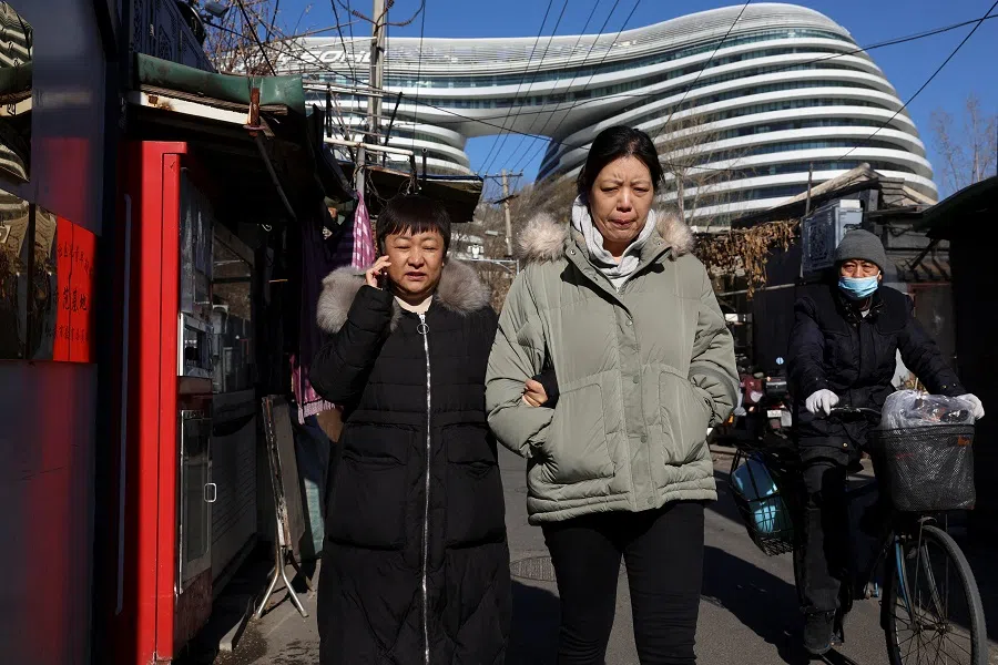 People walk near an office complex in Beijing, China, on 15 January 2024. (Florence Lo/Reuters)