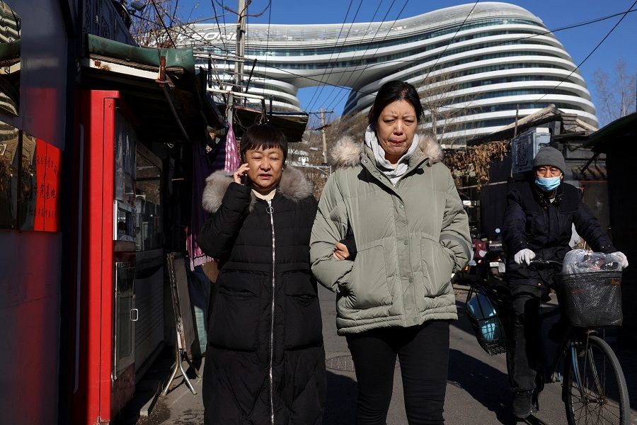 People walk near an office complex in Beijing, China, on 15 January 2024. (Florence Lo/Reuters)