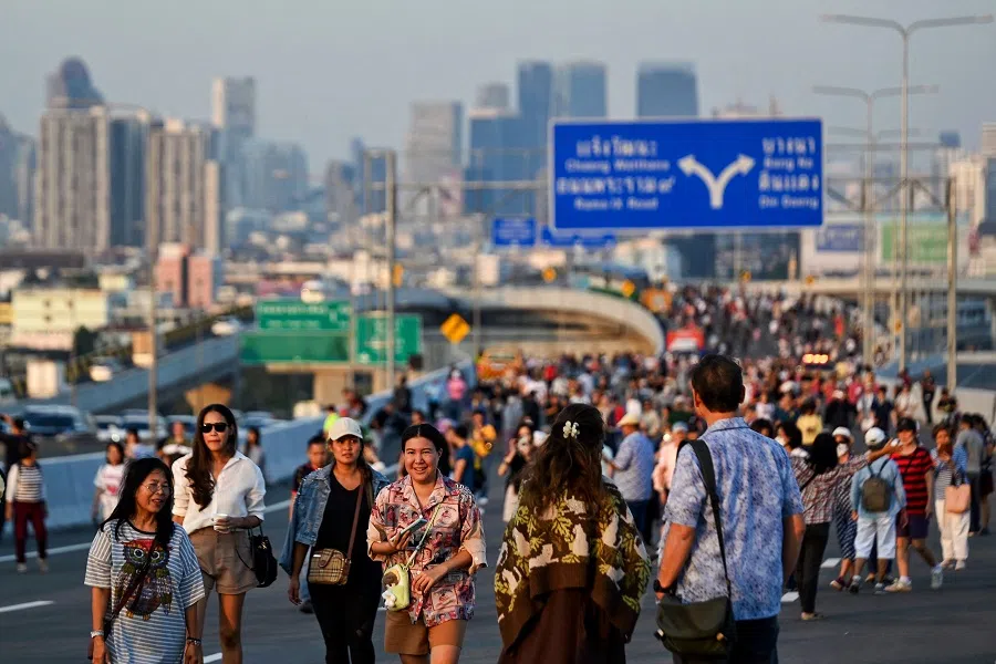 People walk on the Thotsamarachan (Rama X) bridge in Bangkok on 17 January 2025. (Lillian Suwanrumpha/AFP)