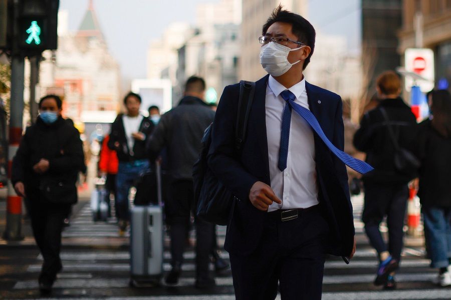 A man wearing a face mask walks on a street in Shanghai, China, 4 March 2021. (Aly Song/Reuters)